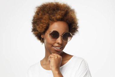 Gri arka planı koyu trendy güneş gözlüğü güzel gösterilen yumruk ile onun çene dokunmadan bakarak gülümsemek hayret ederken flört çekici esmer kadın yatay closeup resimde