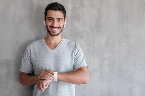 Joven Hombre Guapo Sonriente Con Auriculares Inalámbricos Camiseta Sosteniendo Relojes — Foto de Stock