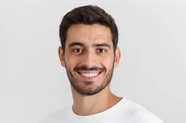 Portre fotoğraf genç gülümseyen Avrupa yakışıklı beyaz casual t-shirt giymiş gri arka plan üzerinde izole
