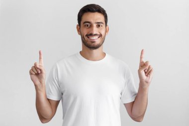 Gün ışığı beyaz t-shirt yakışıklı adamın gri arka plan üzerinde izole iki parmağınızla işaret eden oktan yukarı vurdu