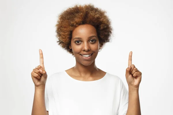 美丽的非洲裔美国妇女在白色 T恤指着两个手指孤立的灰色背景 — 图库照片