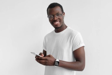 Seyir ve arkadaşları smartphone, gri arka plan üzerinde izole kullanarak, manifatura süre neşeli ifade kamerayla gülüp zenci