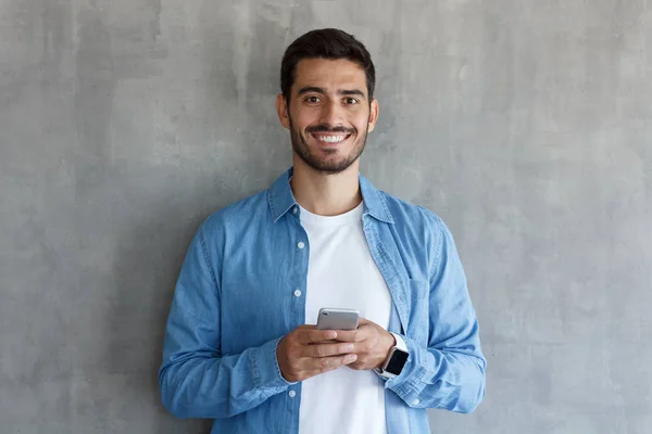 Retrato Atractivo Joven Hombre Camisa Azul Sosteniendo Smartphone Mirando Cámara —  Fotos de Stock