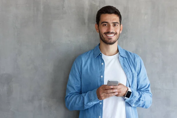 Retrato Joven Guapo Con Camisa Azul Sosteniendo Teléfono Inteligente Mirando —  Fotos de Stock