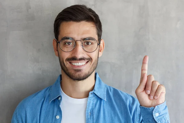 Pohledný Usměvavý Mladý Muž Modré Košili Ukázal Prstem Izolované Šedé — Stock fotografie