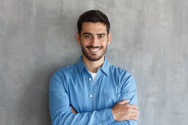 Yakışıklı beyaz yatay atış rahat kıyafetler, kendinden emin ve iyimser, gülümseyen dostu ve mutlu bir şekilde poz süre arıyorsunuz içinde geçti silah ile ayakta resimde izole üzerinde gri arka plan adam