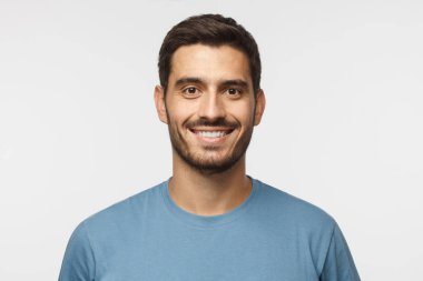 Mavi t-shirt gri arka plan üzerinde izole genç gülümseyen yakışıklı adam portresi kapatın