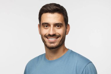 Genç yakışıklı Avrupa beyaz adam gri arka plan üzerinde izole headshot. kendinden emin ve rahat görünümlü mutlu ve dostu kameraya, gülümseyen rahat mavi t-shirt, giyen