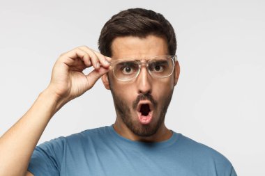 Mavi t-shirt bağırarak, kızgın genç erkek gözlük tek elle tutarak şok içerik ile crabbed
