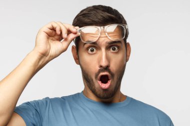 Açık ağız, düşük fiyat ve satış tarafından sürpriz ile Omg bağırarak, şeffaf gözlük tutan mavi tişört genç adam