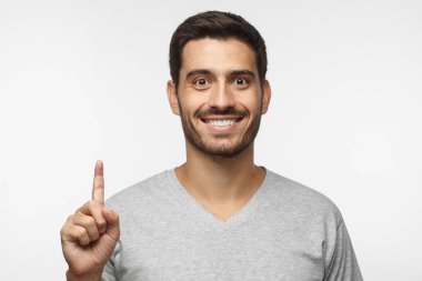 Gri arka plan üzerinde izole parmağıyla yukarıyı çekici genç adam