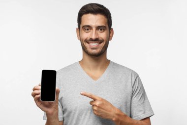 Boş telefon ile izole gri arka plan üzerine boş siyah perde tutan genç gülümseyen adam