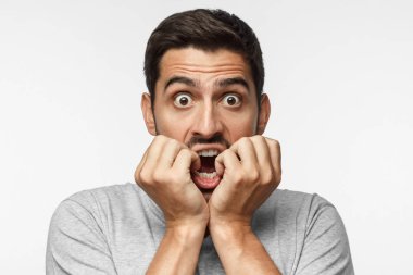 Yakışıklı ve yuvarlak eyes ile ağız kapsayan, derin şaşkınlık ve korku, gri arka plan üzerinde izole yaşayan genç adam