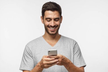 Genç bir adamın akıllı telefon ekranına bakıp arkadaşlarıyla sohbet ederken gülümsediği yakın plan fotoğrafı.