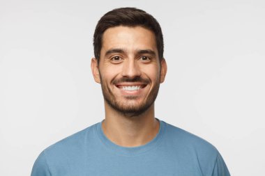 Yakışıklı adam t-shirt gri arka plan üzerinde izole mavi gülümseyen portresi kapatın