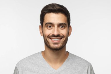 Gri t-shirt gri arka plan üzerinde izole genç gülümseyen yakışıklı adam portresi kapatın