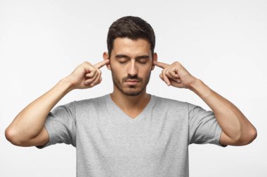 Yüksek sesle müzik veya gürültü ile vurguladı gri t-shirt kapanış kulakları genç adam