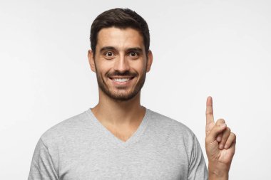 Gri arka plan üzerinde izole onun parmağı ile işaret eden oktan yukarı yakışıklı genç
