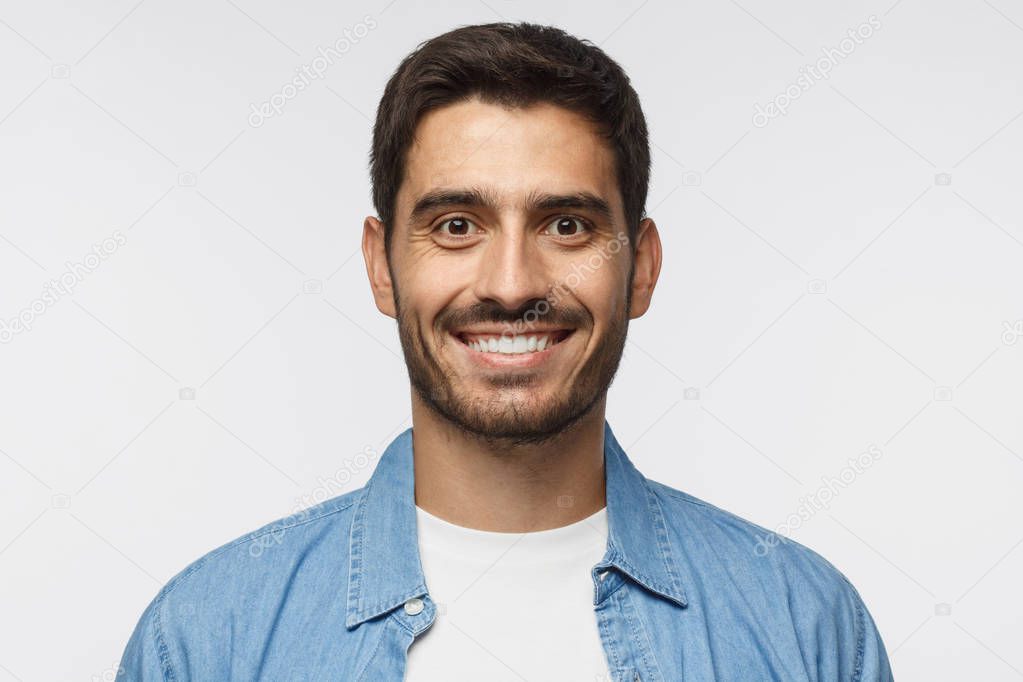 Close up portrait of young smiling handsome student in blue denim shirt isolated on gray background