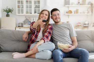 Mutlu çift evde kanepede oturup Tv izlerken