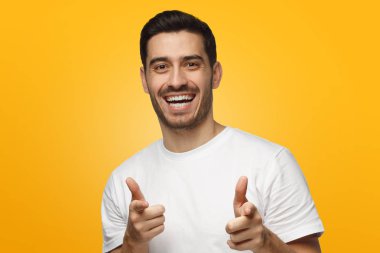 Hey siz! Genç adam kameraya izole sarı arka plan üzerinde parmak ile işaret