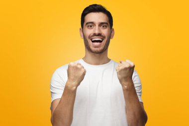 Genç adam kazanan, çığlık, ise zaferini kutluyor mutluluk ve şans, ifadesinde Yumruklarını sıkma izole sarı zemin üzerine