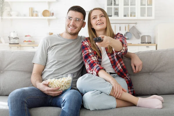 年轻的幸福夫妇看电视 愉快的家庭坐在沙发上与爆米花碗 — 图库照片