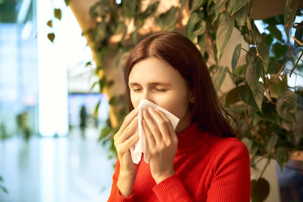 Una donna frustrata starnutisce a causa di allergie al centro commerciale. Il concetto di esacerbazione primaverile di allergie, naso che cola, raffreddore — Foto Stock