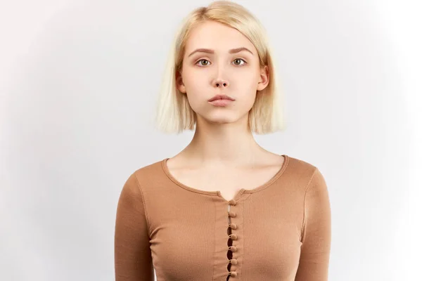 Güzel kız Fotoğraf kamera ciddi bir görünüme sahip, açık sarı kahverengi saçlı, nazik bir gülümseme var, onun doğal güzelliğini gösterir. Kadın reklam için kopya alanı ile beyaz arka plan karşı pozlar