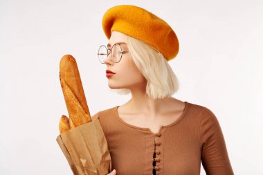 Sarışın, sarı bereli genç bayan bagetlerle sarılır ve beyaz arka planda izole bir şekilde eğlenir.