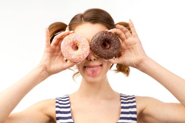 Gözleri sırlı donut ve eğlenceli bir gülümseme önce tutarak çekici genç kız dil gösterir. İzole arka plan da yakın çekim portre