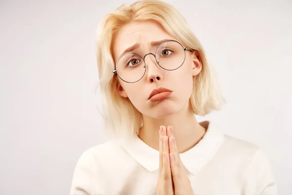Słodka Europejska Blondynka trzyma ręce w gestu modlitwy, usta są dociskane, a jej oczy pokazują prośbę, żebranie o coś. Izolowane na białym tle w Studio — Zdjęcie stockowe
