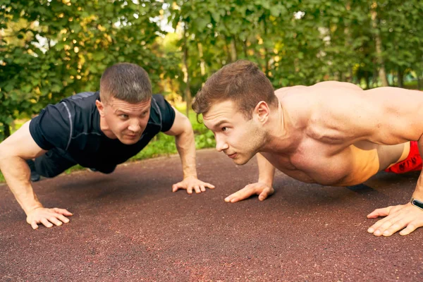 Homens equipe faz push-UPS na rua em campo de esportes — Fotografia de Stock