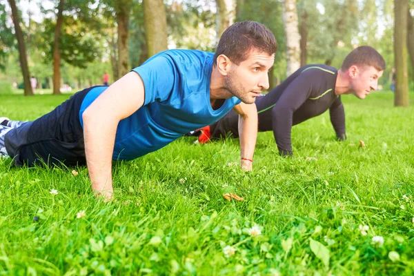 Homens equipe faz push-UPS na rua em campo de esportes — Fotografia de Stock