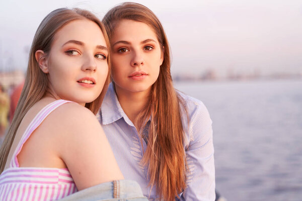 Pretty student girls enjoy sunset on a sea shore. 