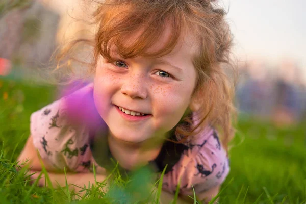 柔らかい緑の草の中に横たわる小さな子供を微笑む. — ストック写真