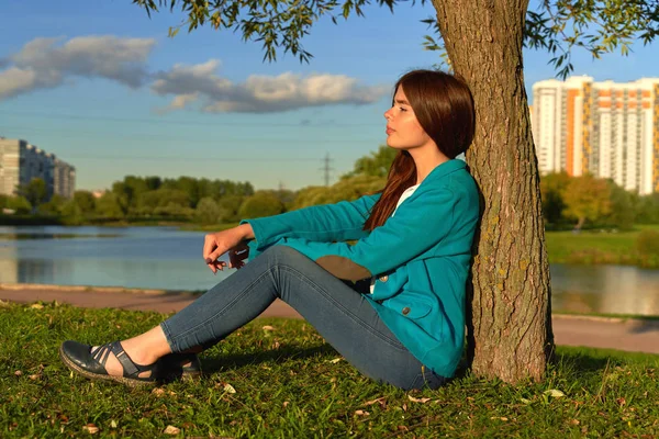 Młoda ładna kobieta odpoczywa pod drzewem w pobliżu jeziora — Zdjęcie stockowe