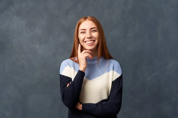 Young girl in warm blue sweater isolated on wall.