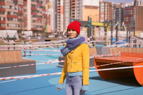 Photo de sports fermés Aire de jeux dans les rues désertes de quartier résidentiel pendant la quarantaine scellée avec bande de clôture interdisant le passage. Femme est fatiguée quarantaine est sorti, regarde où se reposer Photo De Stock