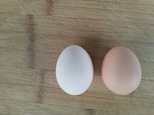 木板上有两个不同颜色的蛋 — 图库照片