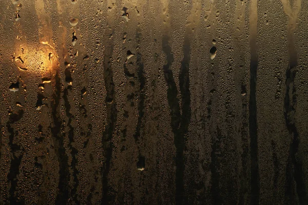 view of a sunset through water drops on the misted glass