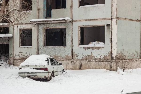 Αυτοκίνητο καλυμμένα με χιόνι στην αυλή του εγκαταλελειμμένα σπίτια. μικρό βάθος Εικόνα Αρχείου