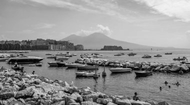 A black and white picture of people sunbathing next to resting boats in the Chiaia district (Naples). clipart