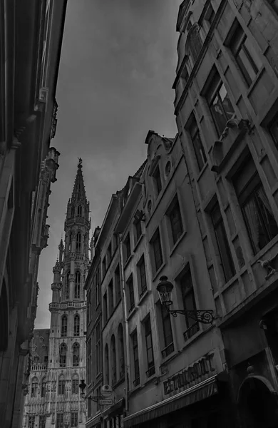 A black and white picture of the Grand Place as seen between nearby buildings (Brussels).