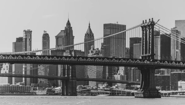 A black and white picture of the Manhattan Bridge overlooked by the skyscrapers of Lower Manhattan.
