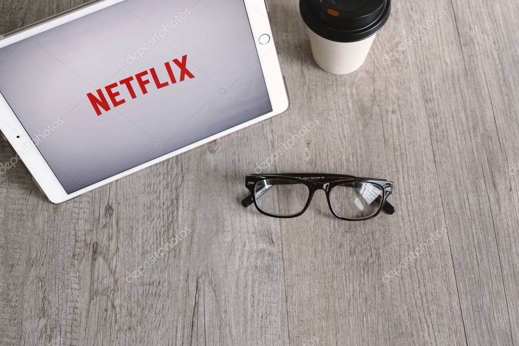 BANGKOK, THAILAND - April 28, 2018 : Netflix app icon on ipad tablet screen with eyeglasses and coffee. Netflix is an international leading subscription service for watching movies and TV series.
