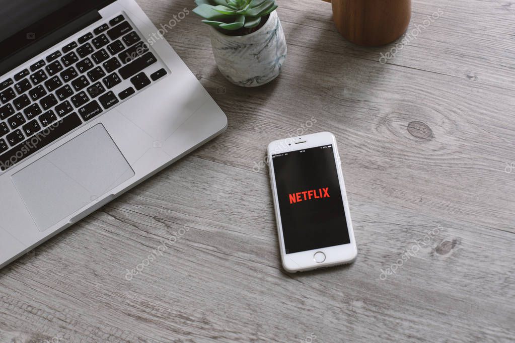 BANGKOK, THAILAND - April 28, 2018 : Workspace desk and Apple iphone showing Netflix app icon on screen. Netflix is an international leading subscription service for watching movies and TV series.