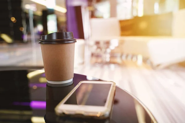 Take away coffee cup empty blank copy space for your design text or banner of brand and smartphone on the table in the cafe