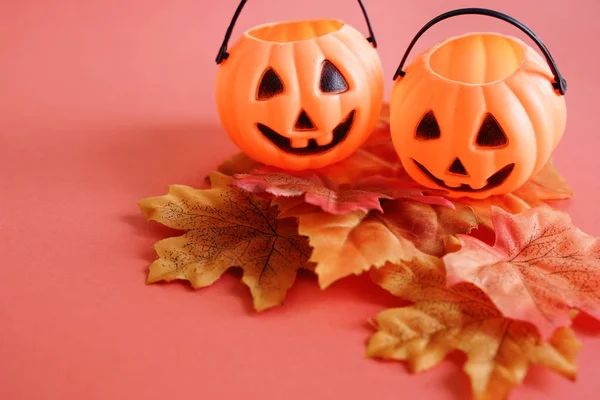 Jack O lantern pumpkins face on autumn leaves with orange background, halloween concept