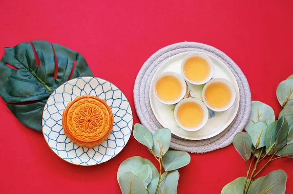 熱いお茶と赤の背景に 休日やお祭りのコンセプトに緑の植物に中国の月餅のフラット レイアウト — ストック写真